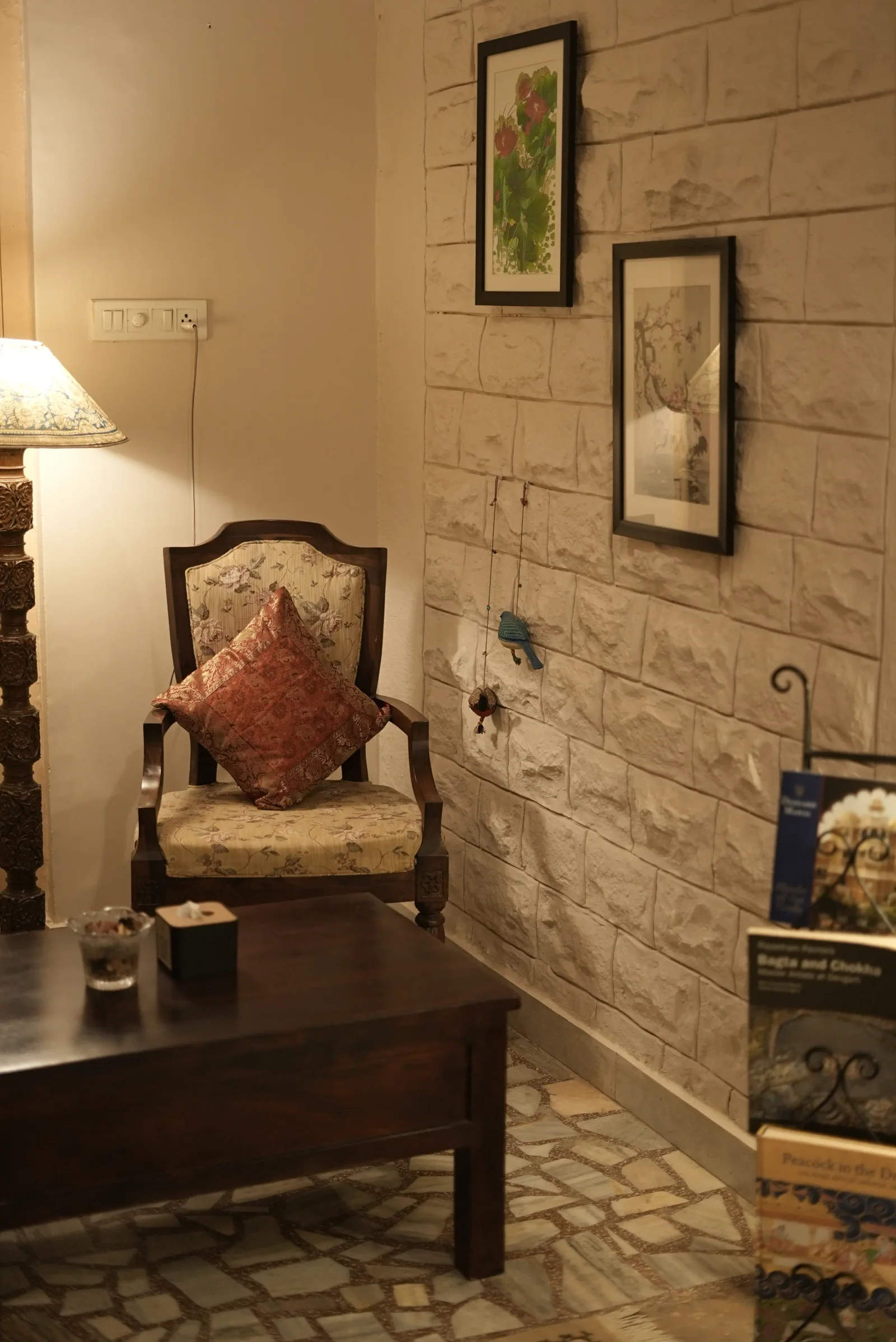 A carved wooden armchair with a cushion in a quiet reading corner at Saanjh The Bistro, Jodhpur