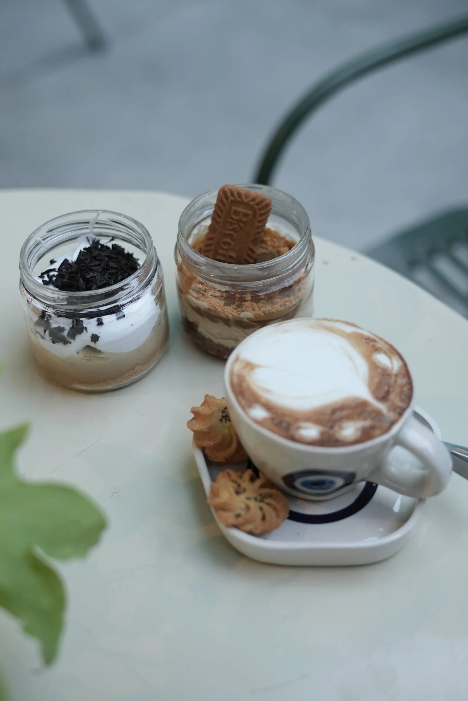 A cappuccino with latte art beside two layered dessert jars at Saanjh The Bistro, Jodhpur